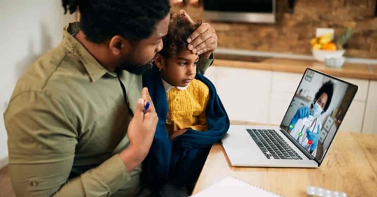 African American father and his sick daughter using laptop while having video call with family doctor.