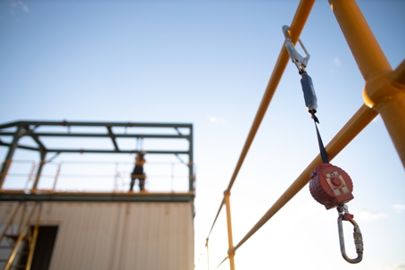 Construction site fall protection safety device clipped to railing