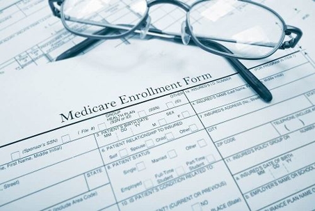Close up of the header of a Medicare enrollment form and a pair of glasses.