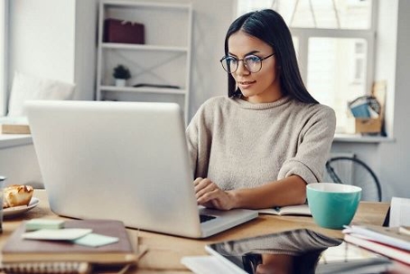 Woman working on a laptop from her home office.