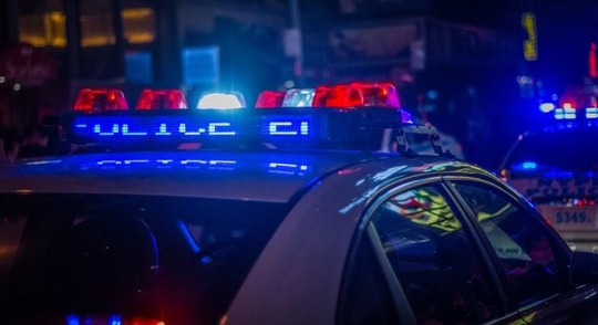 Lights flashing on top of a police car in the city at night.