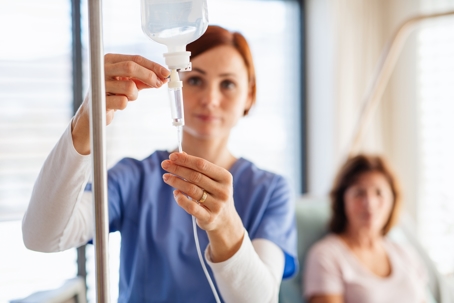 nurse with IV drip and patient in bed