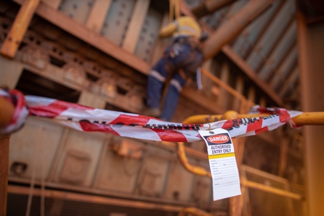 Safety prevention red and white danger tape and tag with construction worker in the background