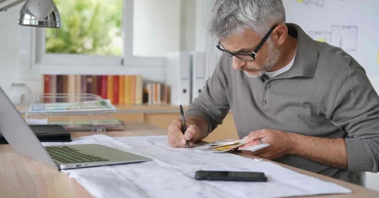 Designer at a drafting table in his office working on project.