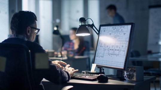 Man working on computer with technical drawings on his screen
