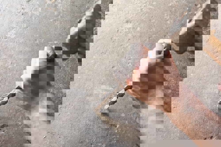 Close-up of hands working with chisel and hammer on stone.