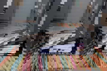 Two binders stacked on top of open file drawer of a metal filing cabinet.