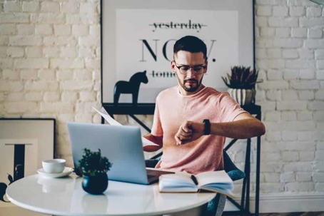 Pensive young businessman checking time on his watch preparing for a deadline.