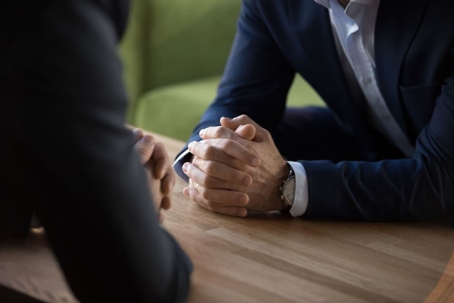 Close up of two businessmen seated across a table to discuss a partnership dispute.