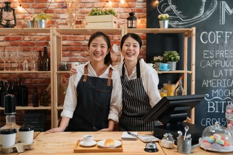 Mother and daughter small business owners women standing behind the counter of their cafe.