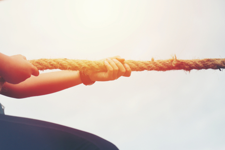Hands pulling on a rope in one direction as in a game of tug-of-war.