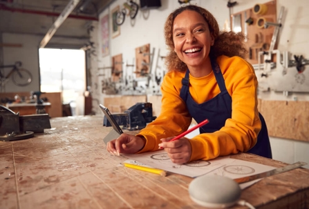 Smiling small business owner drawing product concepts in her workshop.