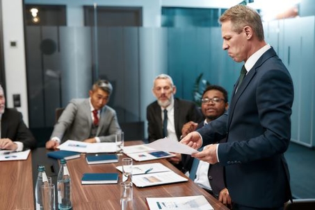 Three businessmen seated around a conference table observing an attorney discussing a dispute in arbitration.