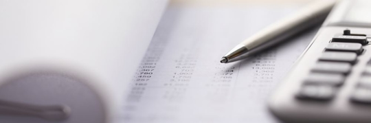 Closeup of a page filled with financial numbers, a pen and a calculator.