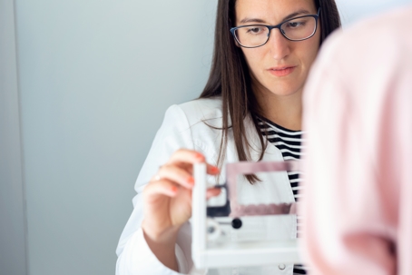 A physician weighing and measuring her patient on the scale during a consultation.