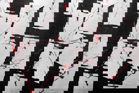 Photo of a black evidence board with blank paper linked by red thread.