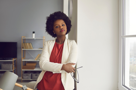 Office worker standing with arms crossed looking thoughtfully at camera.