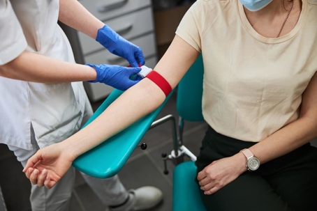 Phlebotomist taking blood in a medical office.