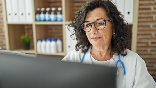 Middle age woman doctor working on a computer in her office at a Medicare clinic.