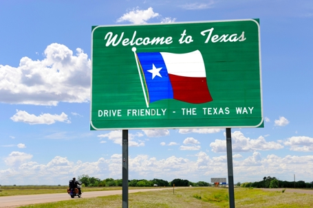 Green "Welcome to Texas" highway sign with an image of the Texas flag.