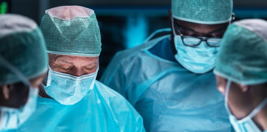 Team of medical doctors performs surgical operation in modern operating room using high-tech technology. Surgeons are working to save the patient in the hospital. Medicine, health and science.