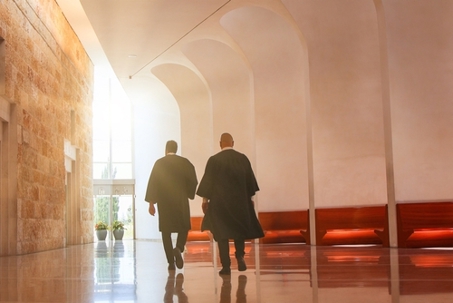 Two robed judges walk down a modern courthouse hallway.