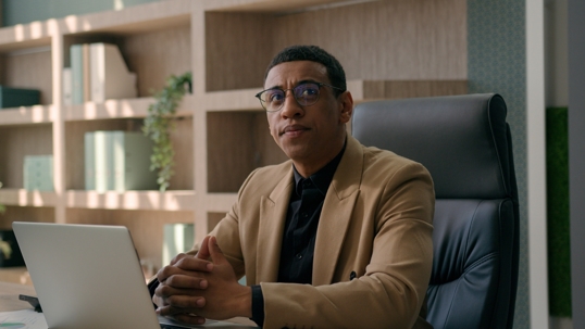 An African American businessman sitting thoughtfully at his desk.