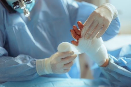 Surgeon applying a bandage after a skin substitute procedure.