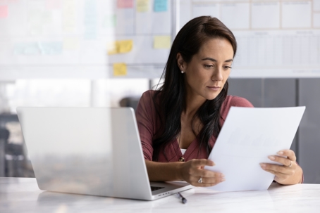 Business professional reading reviewing a legal contract at her desk.