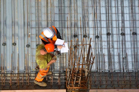 Aerial view of an OSHA compliance officer and construction worker inspecting a construction site.