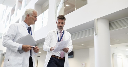 Two doctors talking as they walk through a modern hospital