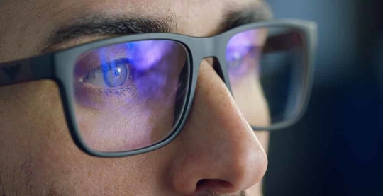 Close up of the eyes behind glasses of a business person looking at a computer screen.