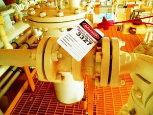 Close-up of an industrial pipe joint with a "danger" label.
