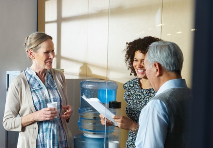 Employees have a casual conversation by office water cooler