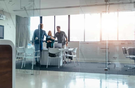 Businesspeople shaking hands before a meeting in a board room.