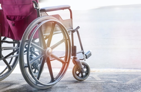 Red wheelchair waiting next to an accessible parking spot