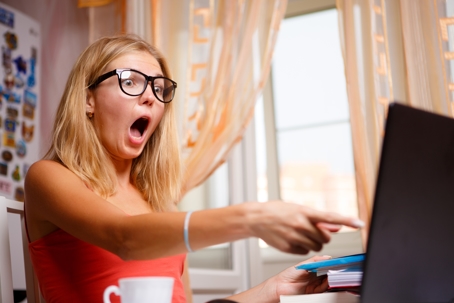 Blonde woman is outraged by what she saw on screen and pointing finger on it