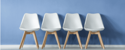 A row of white chairs against a blue wall in a medical office waiting room